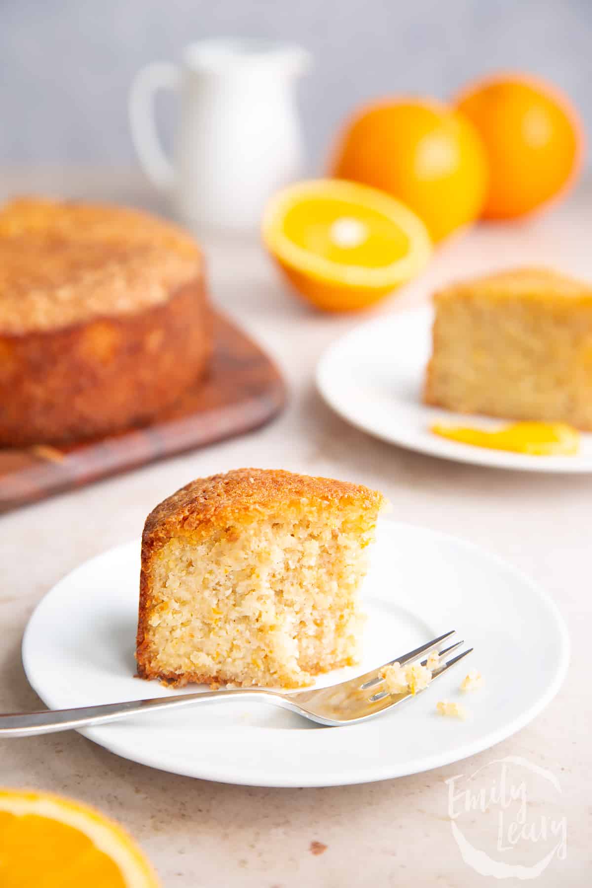 Fork in a finished slice of gluten free orange cake on a white plate.