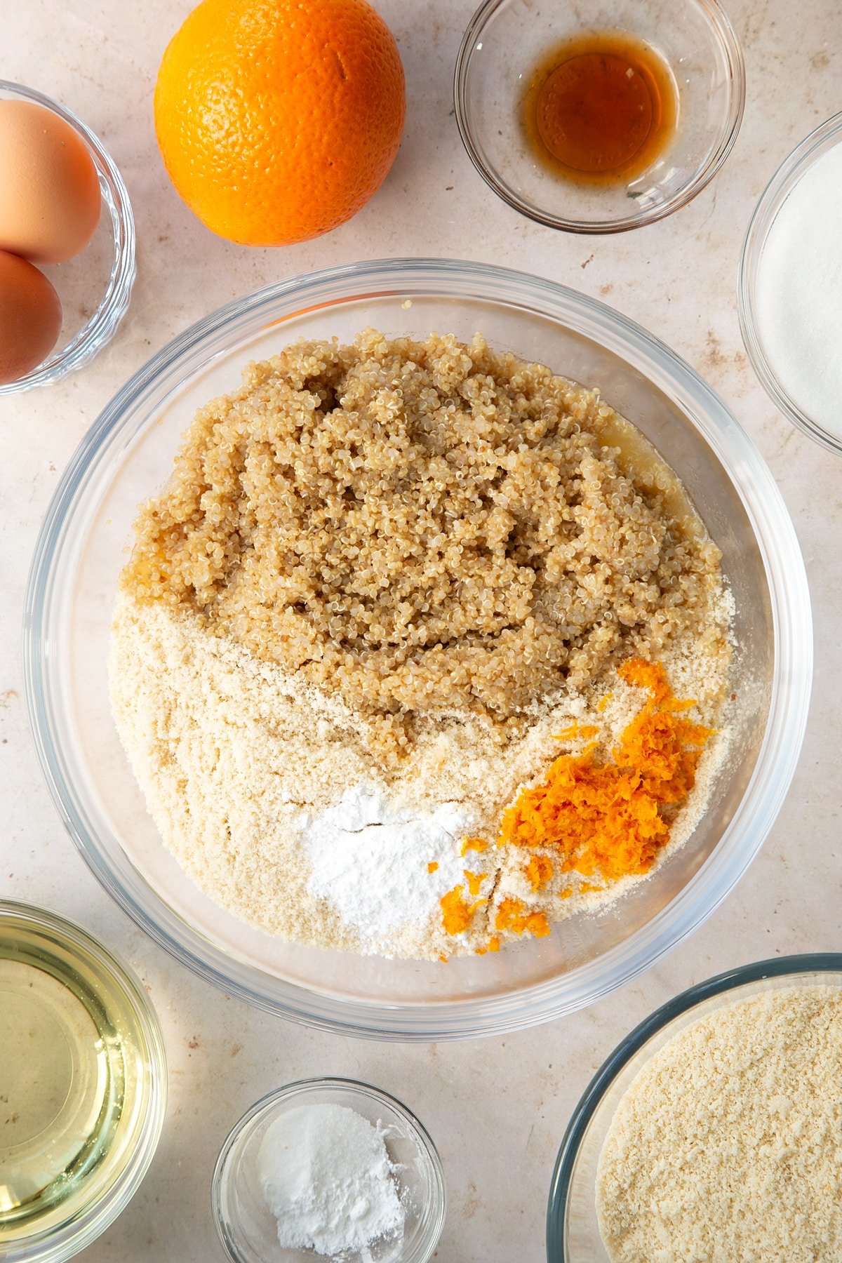 Adding quinoa, baking powder and orange zest to the oil, caster sugar, eggs and vanilla in a large bowl mixture.