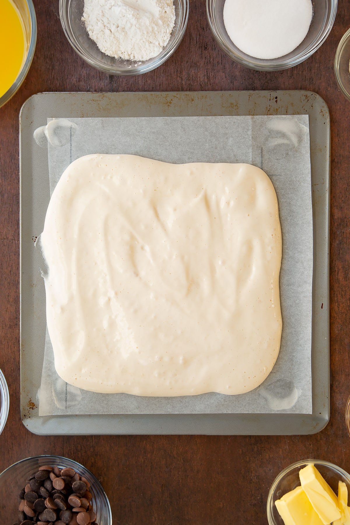 Pouring the wet sponge mixture onto the lined baking sheet. 