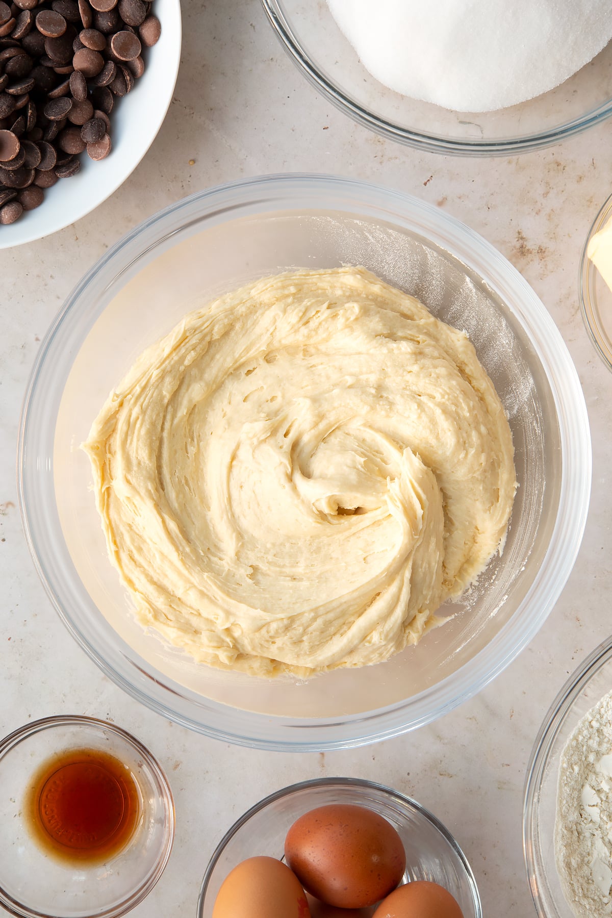 cake batter mixture in a large clear bowl surrounded by ingredients.