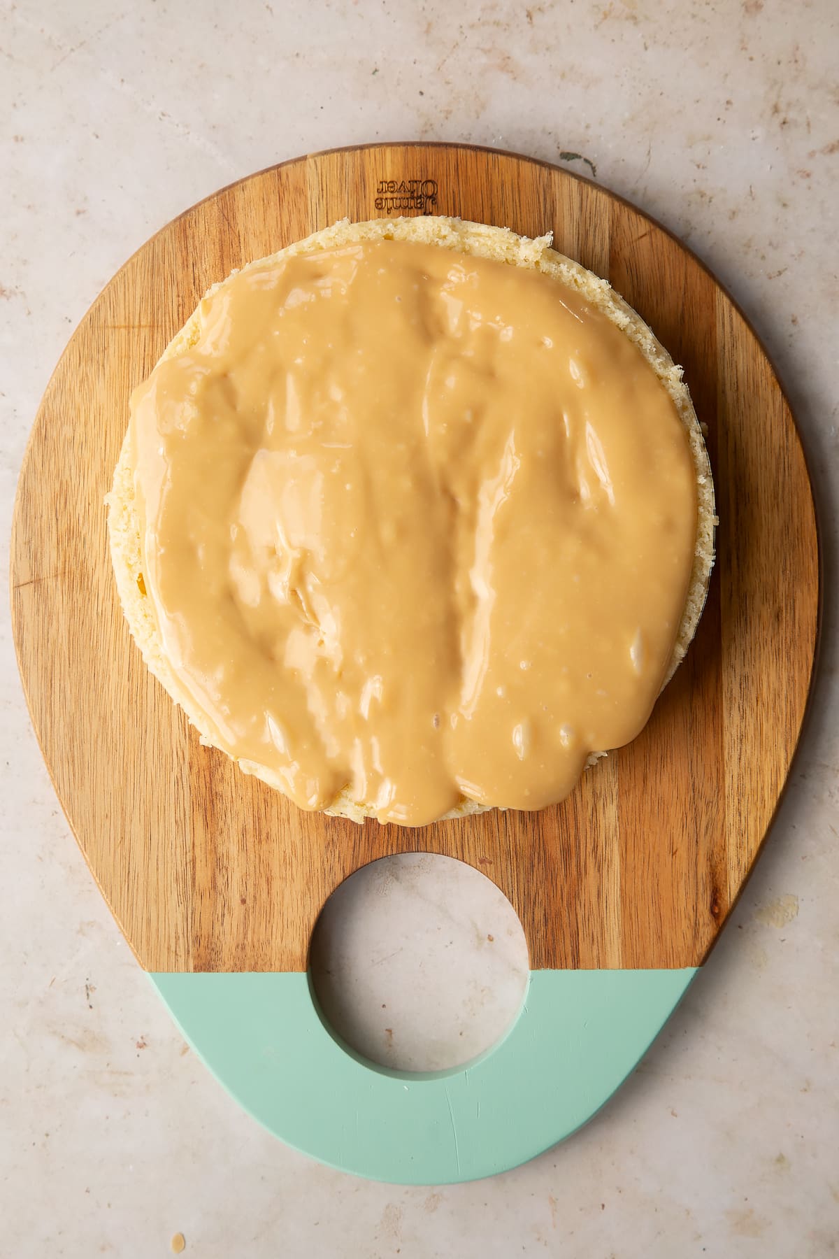 plain sponge cake on a wooden chopping board topped with caramel.