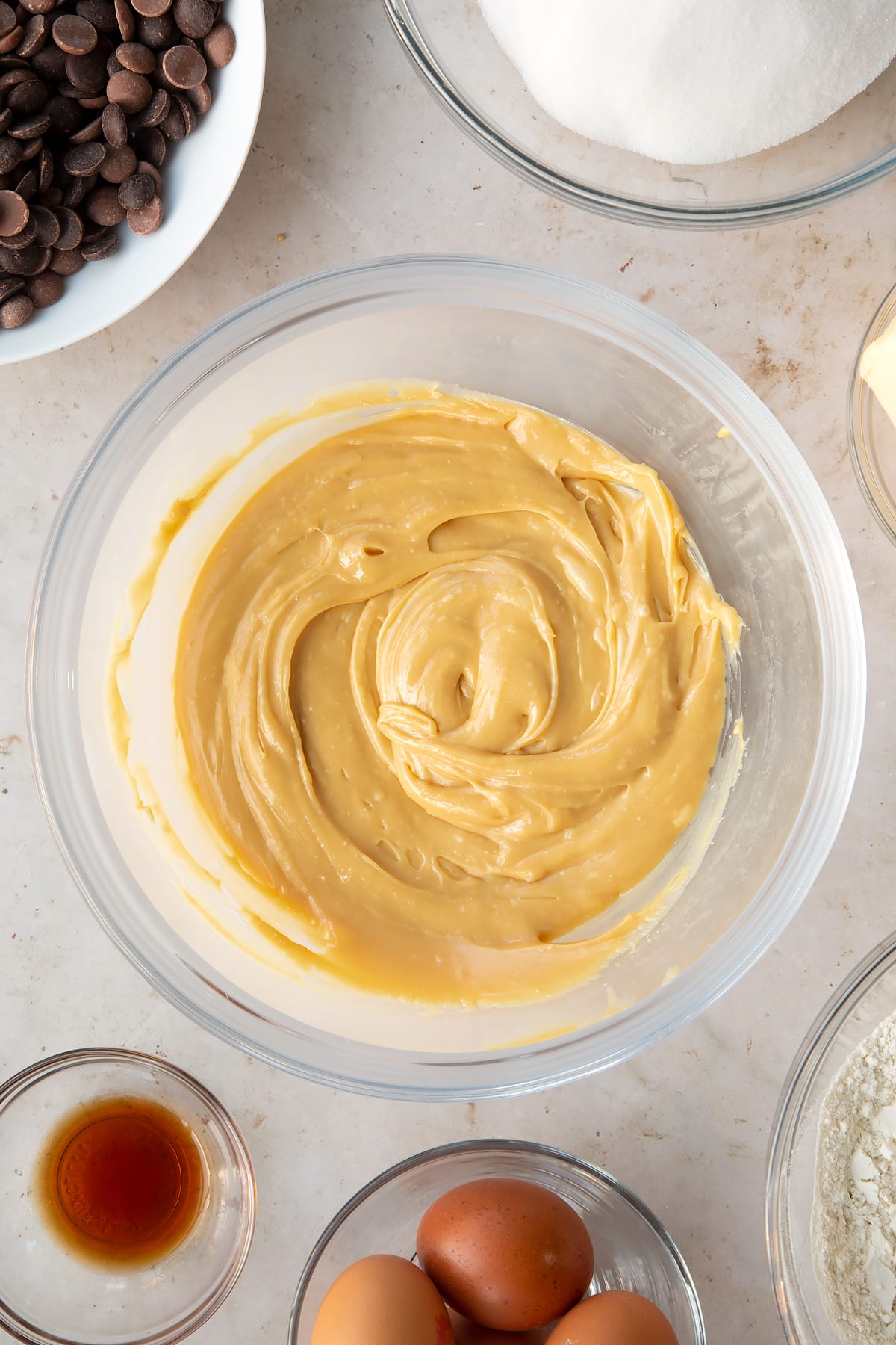 caramel cooling in a large clear bowl surrounded by ingredients.