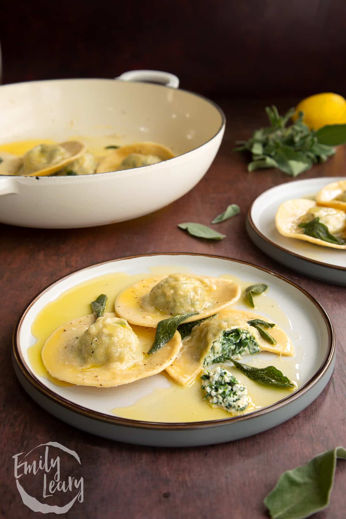 A plate of spinach and ricotta ravioli with one of the ravioli pieces cut open.