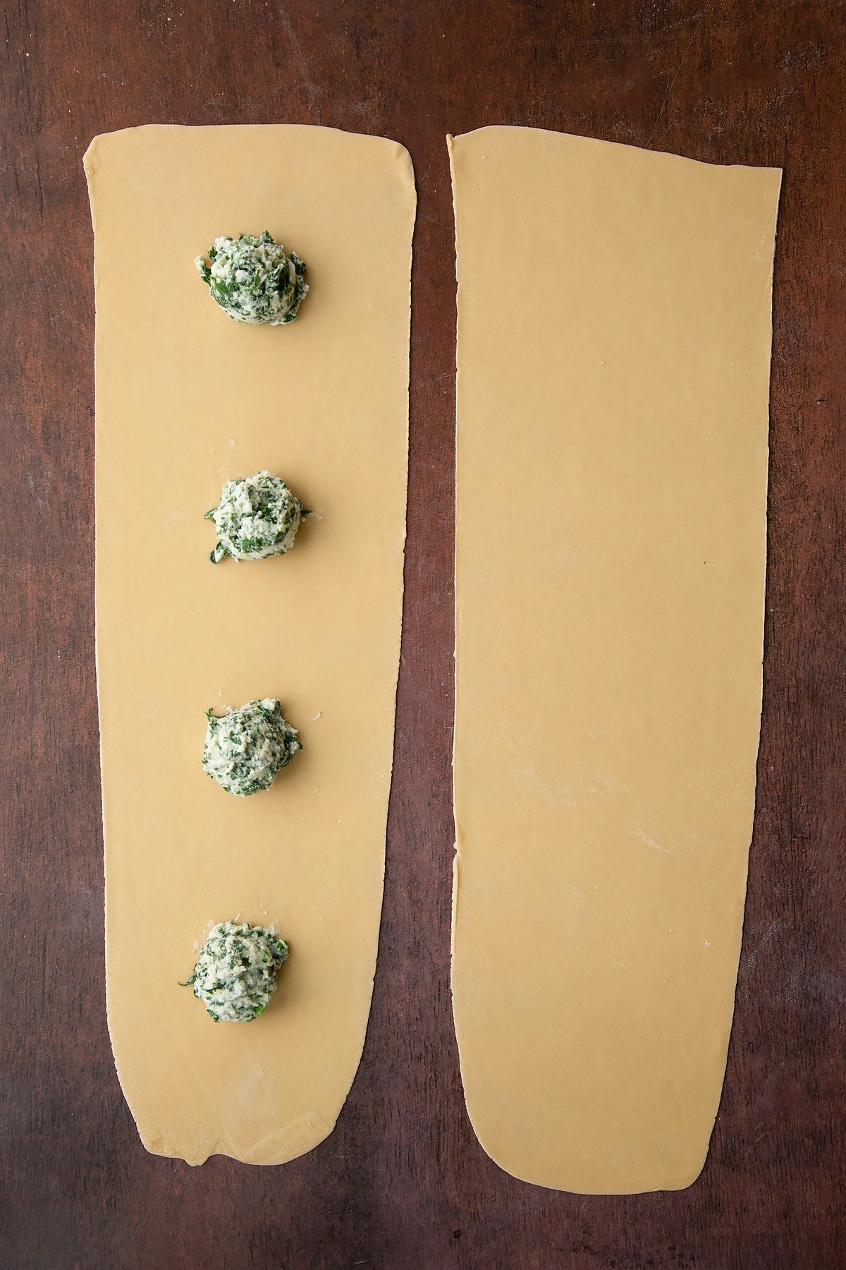 Adding balls of the ricotta and spinach mixture to the pasta sheet.