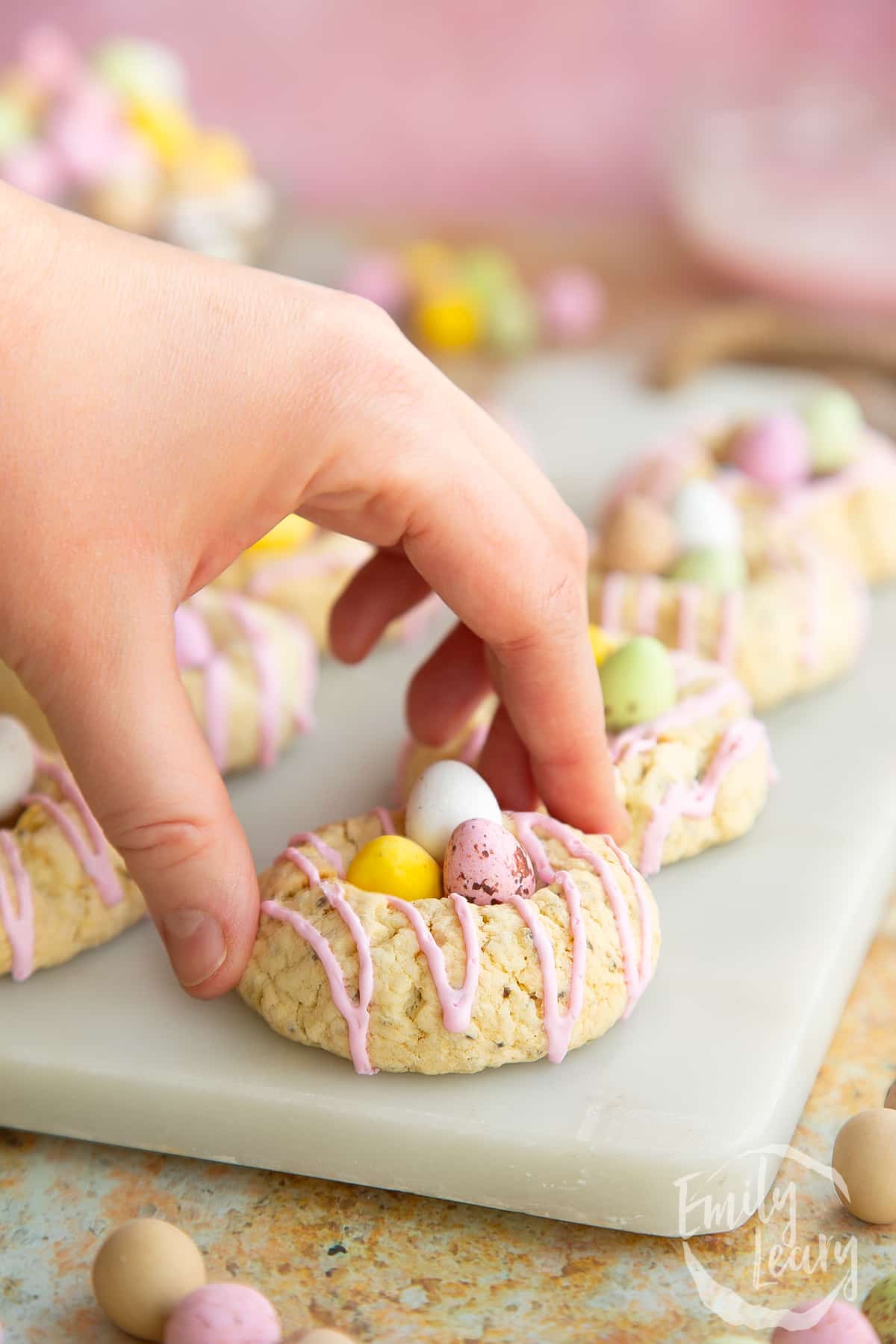 Hand reaching into grab one of the finished vegan easter biscuits.