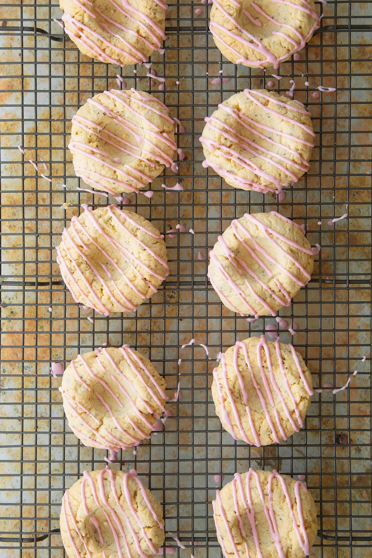 Overhead shot of the icing sugar being drizzled over the biscuits which are cooling on a wire rack.