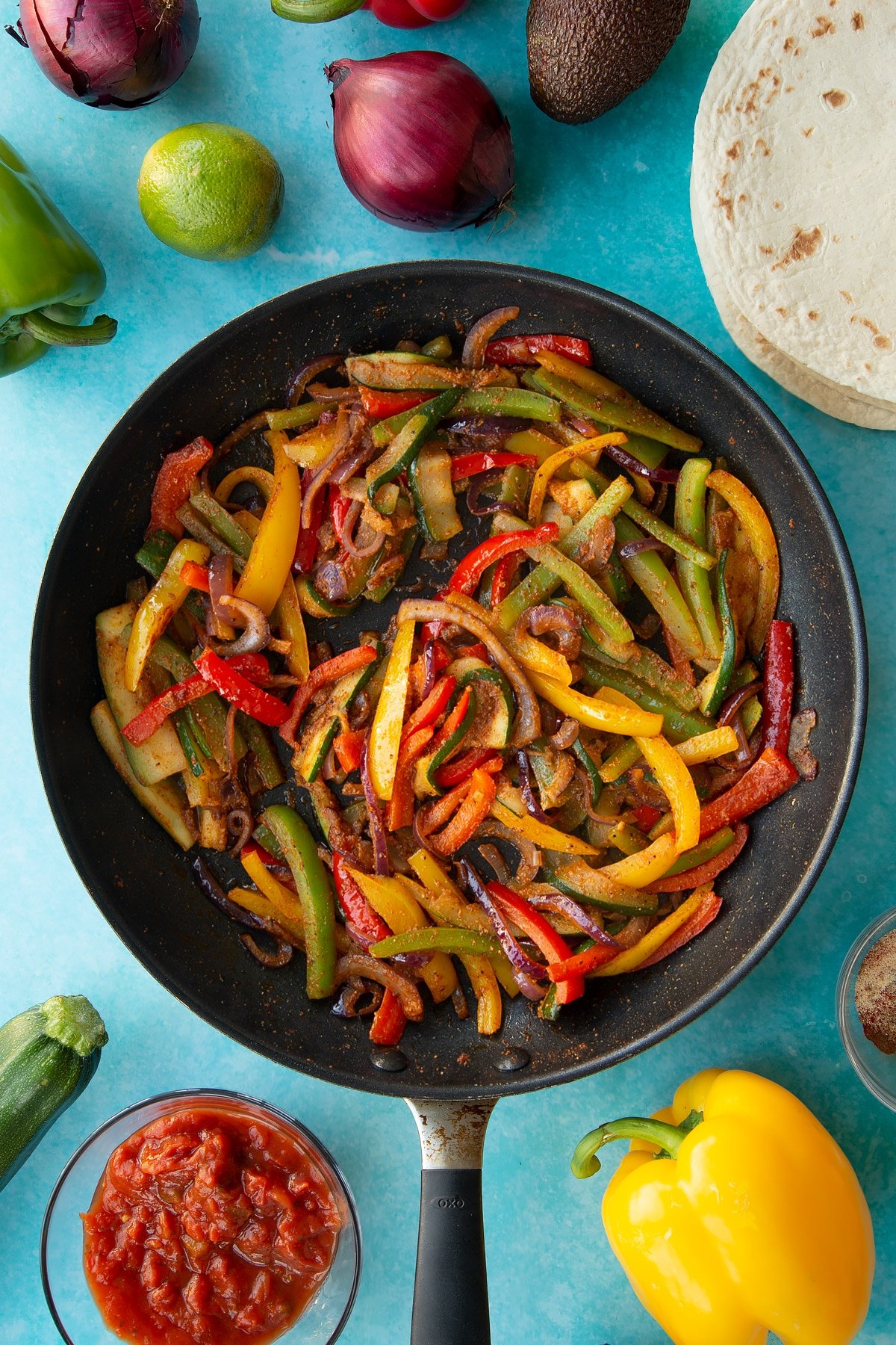 Stirring in the fajita spice to the sliced vegetables in the frying pan.