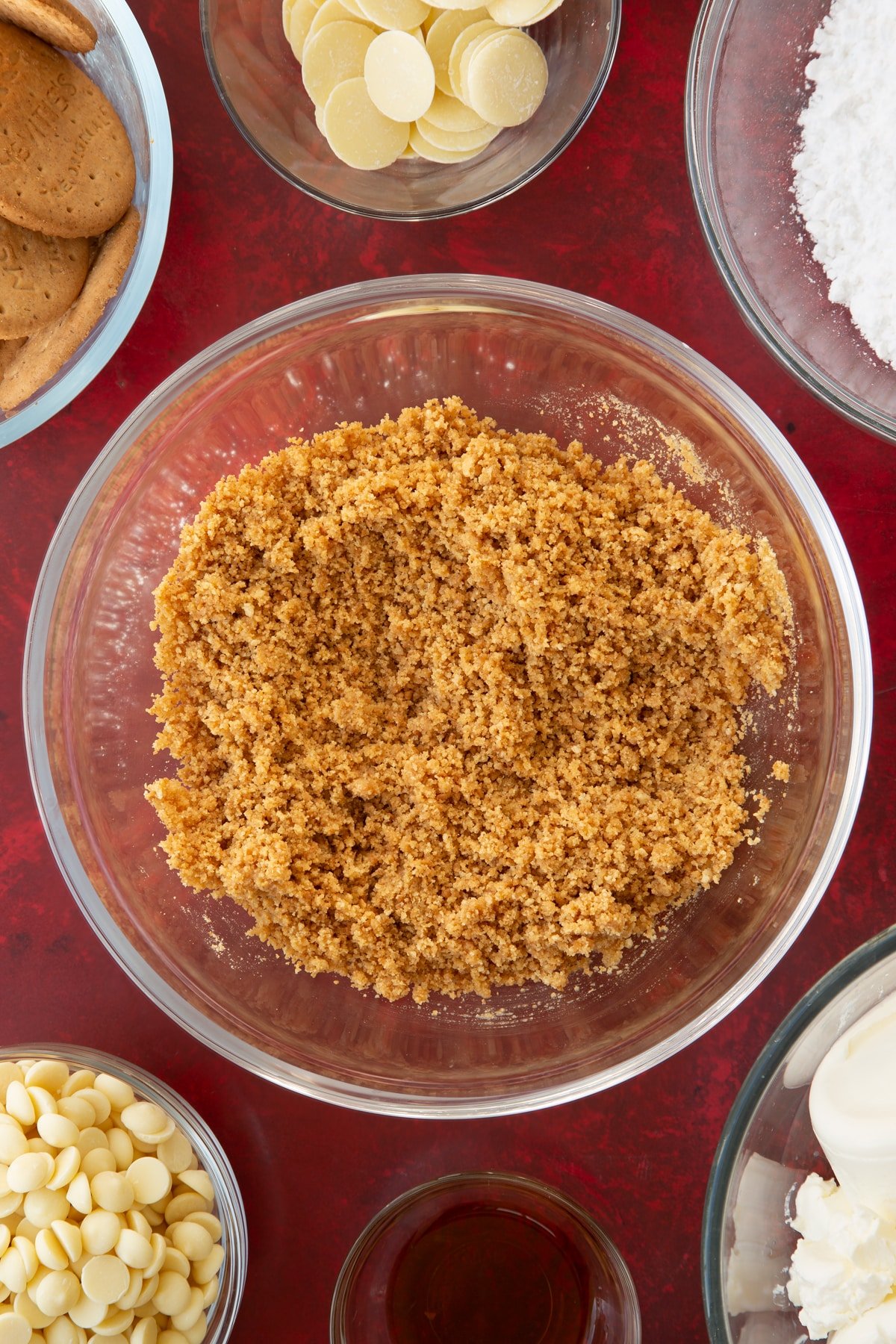 melted butter mixed with crushed biscuit crumbs in a large clear bowl.