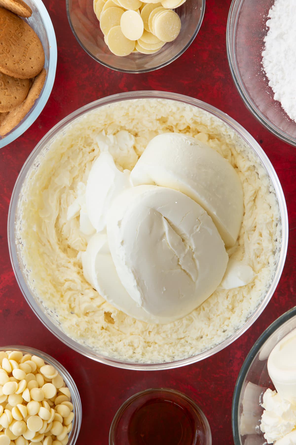 whisked double cream and icing sugar mix in a large clear bowl topped with cream cheese.