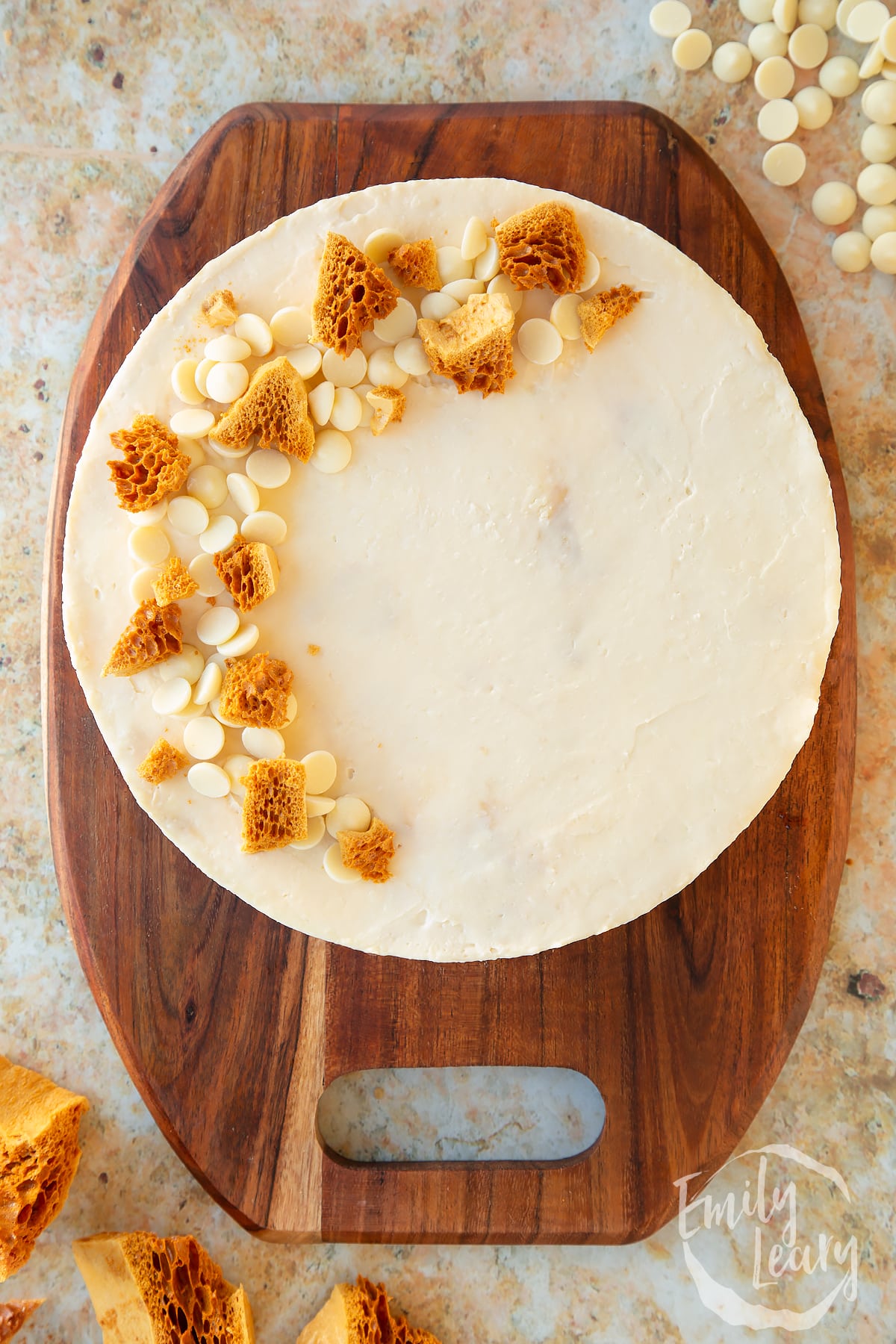 an overhead view of a White chocolate and honeycomb cheesecake on a wooden chopping board.