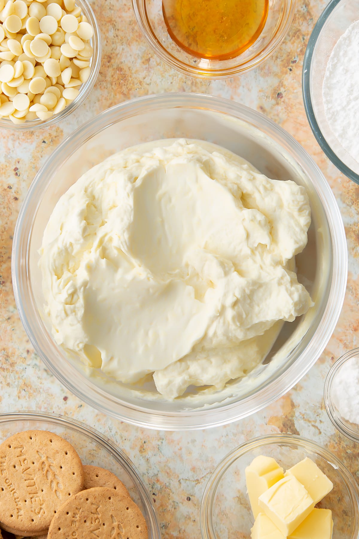 whisked white chocolate cheesecake topping in a large clear bowl.