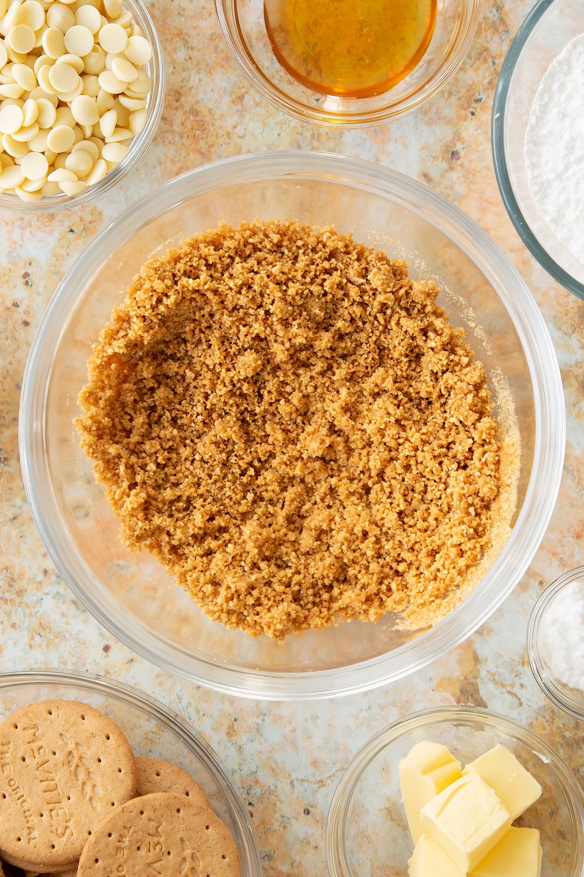 mixed butter and crushed biscuit crumbs in a large clear bowl.