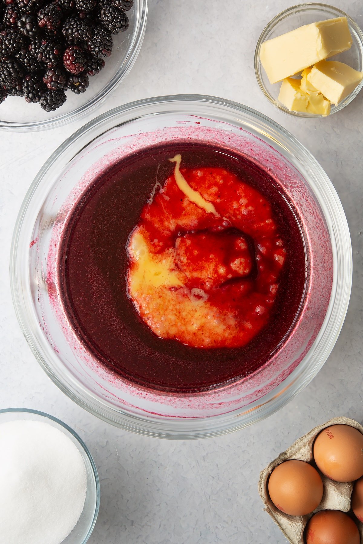 blackberry juice mixture topped with beaten eggs in a large clear bowl.