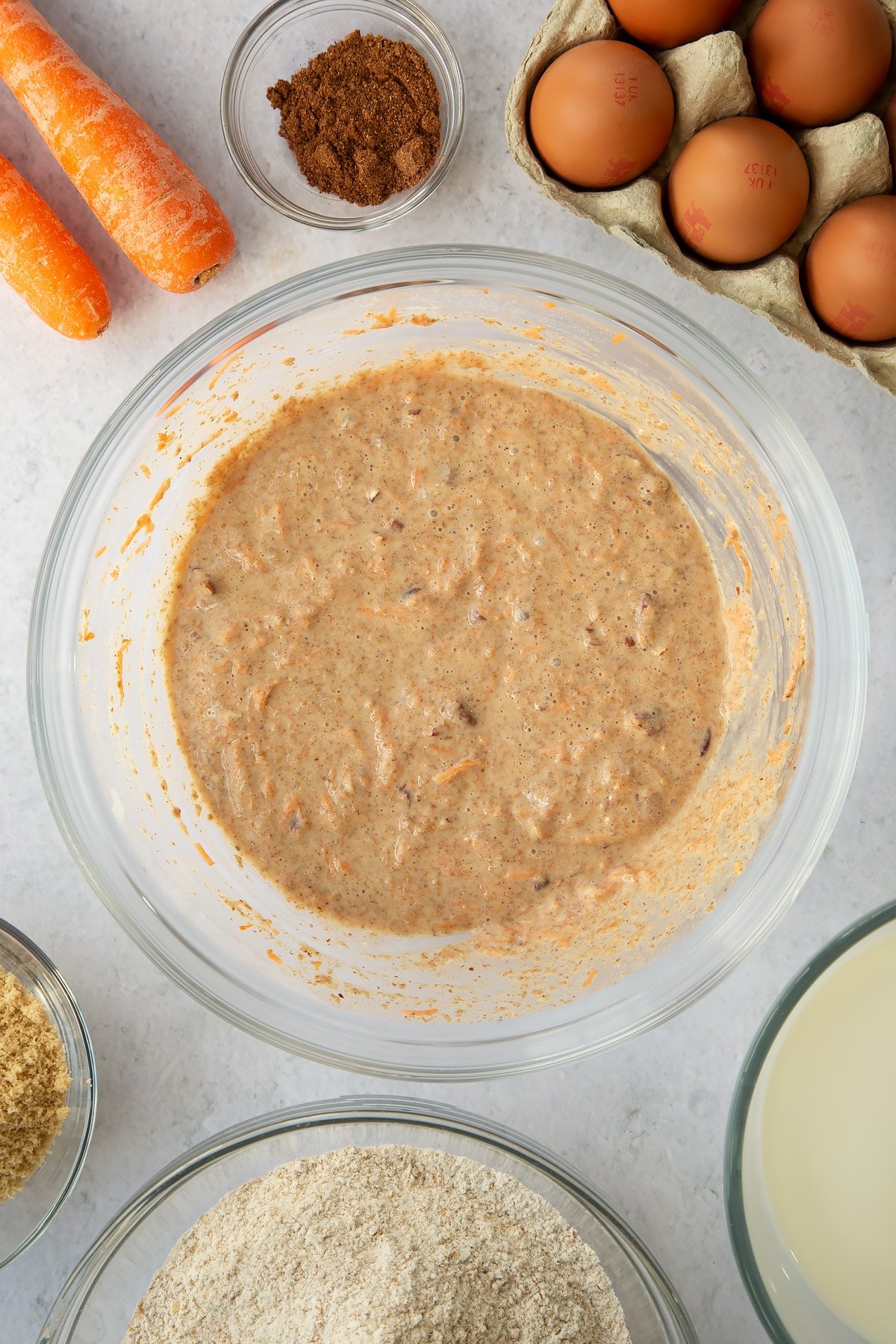 mixed carrot cake batter in a large clear bowl.