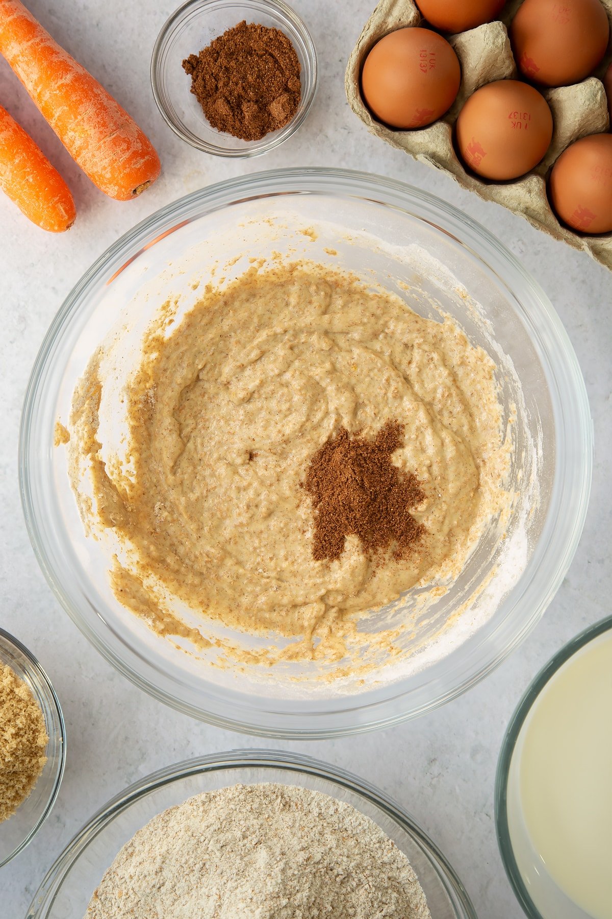 whisked egg, sugar and flour mixture in a large clear bowl topped with mixed spice.