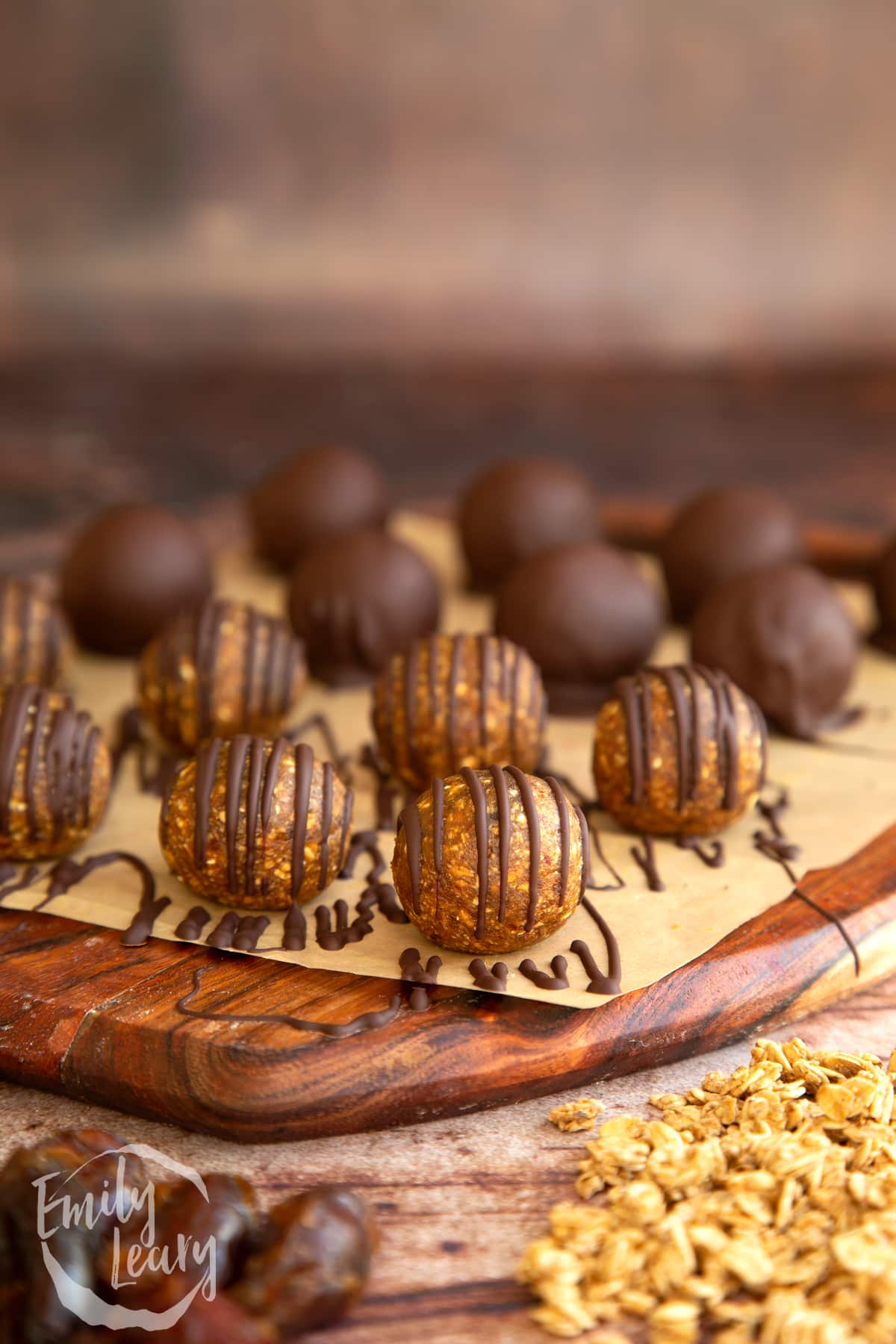 round Date energy balls drizzled with chocolate on a wooden chopping board. 
