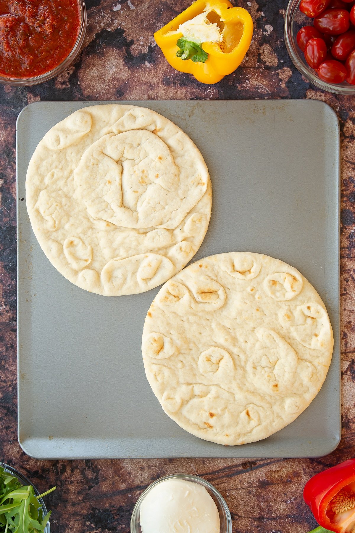 2 plain flatbreads on a metal baking tray.