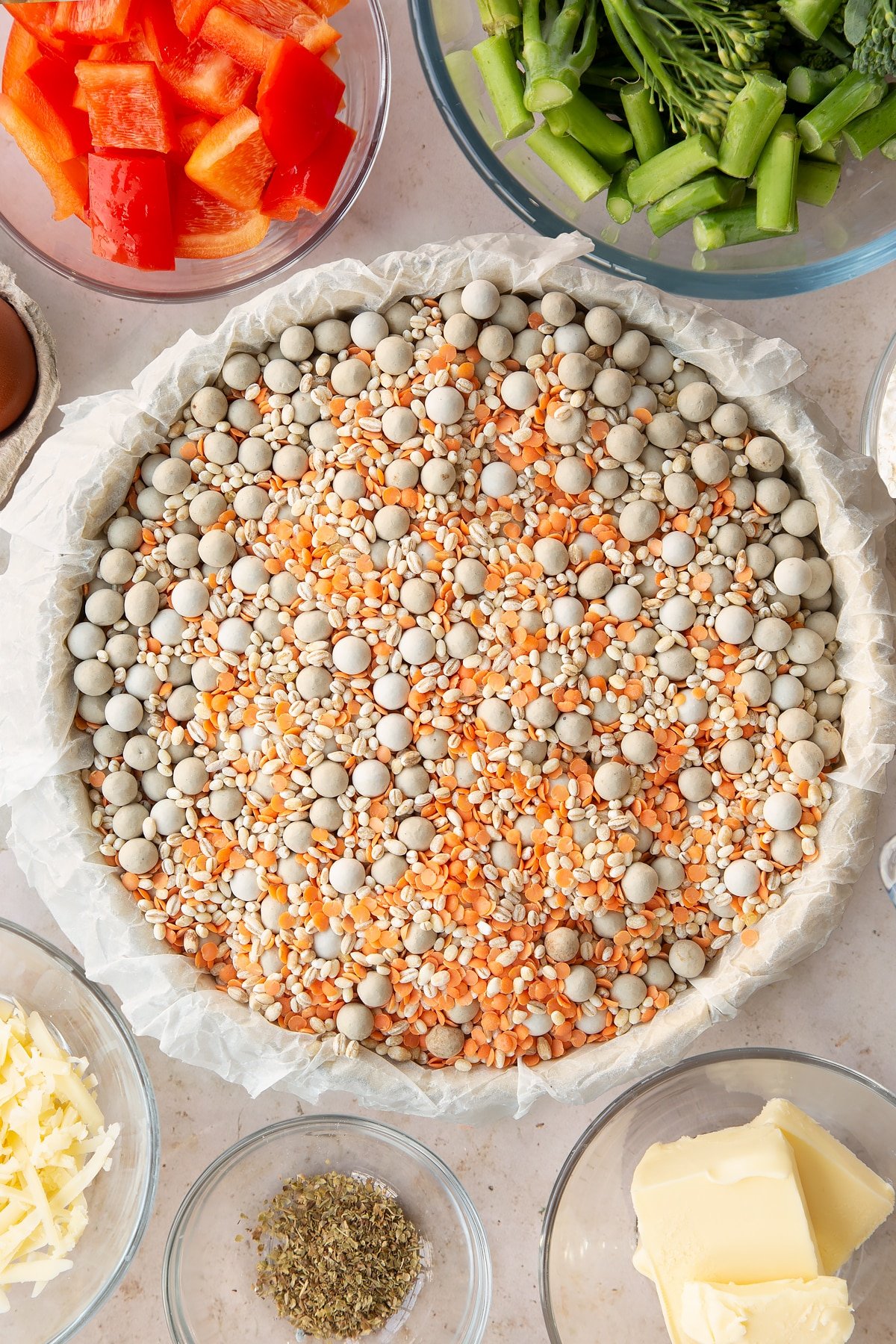 raw shortcrust pastry in a pastry dish covered with baking paper filled with baking beans.
