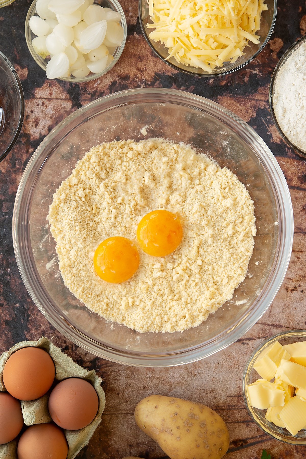 Overhead shot of the eggs and dry mixture in a clear mixing bowl.