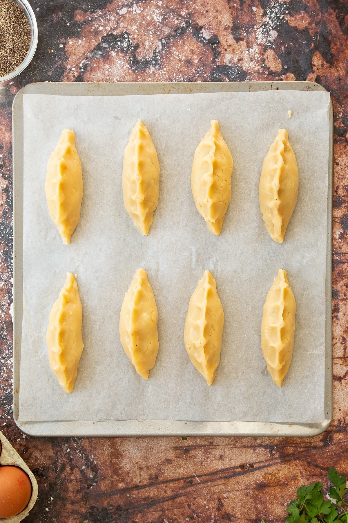 Overhead shot of the finished mini cornish pastries on a baking tray.