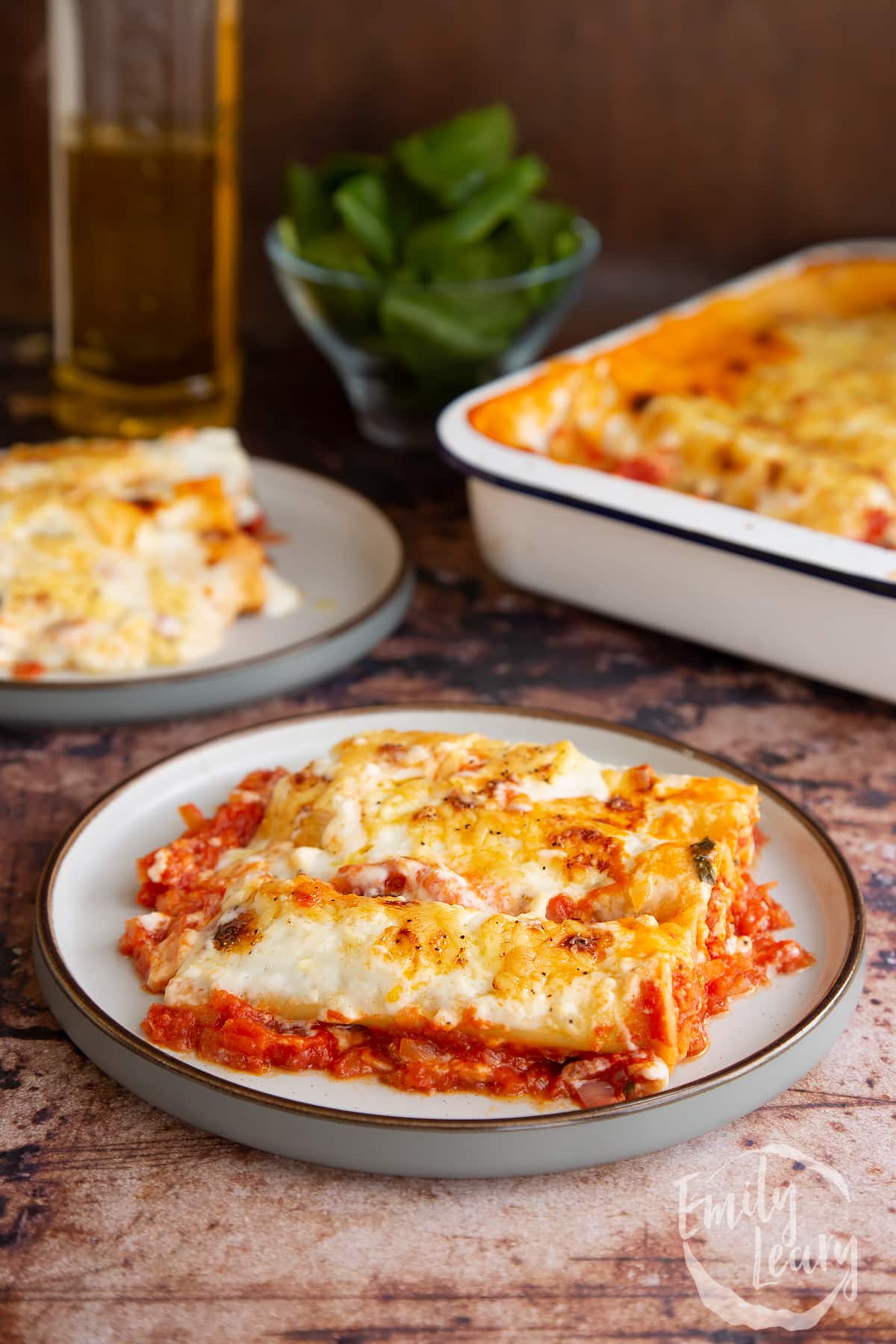 Two plates of Spinach and ricotta cannelloni on a wooden table. 