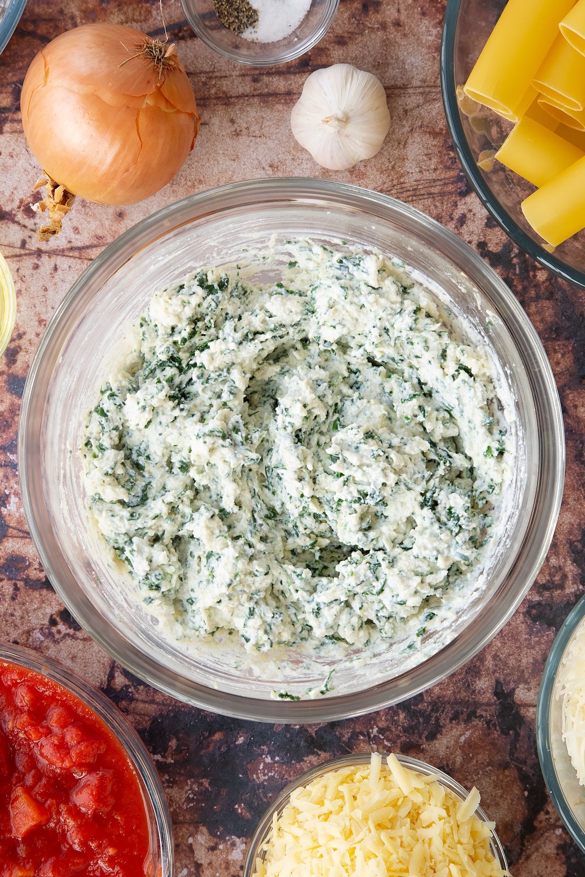 Overhead shot of a bowl of the ingredients mixed together that are required to make the Spinach and ricotta cannelloni.