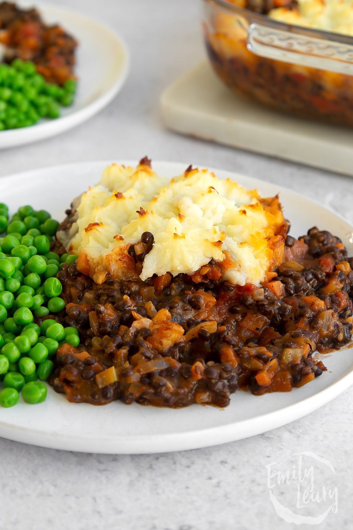 A piece of Vegetarian shepherd's pie on a white plate with peas.