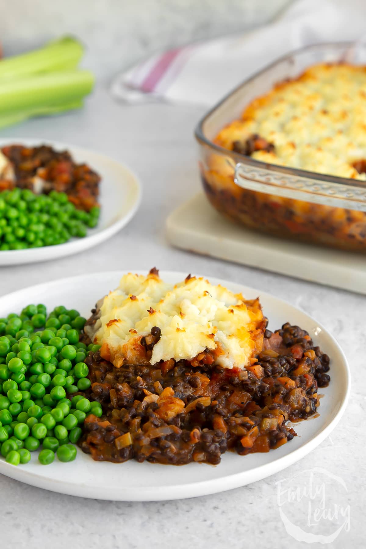 A piece of Vegetarian shepherd's pie on a white plate with peas.