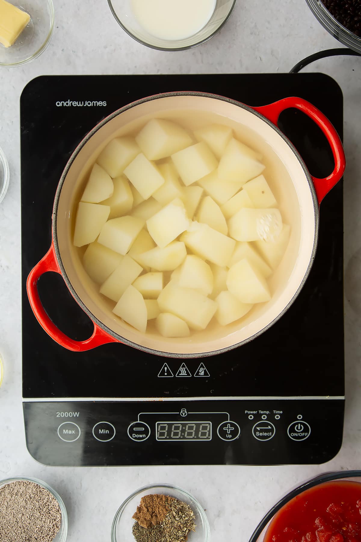 a pan on an induction hob with chopped potatoes in water.