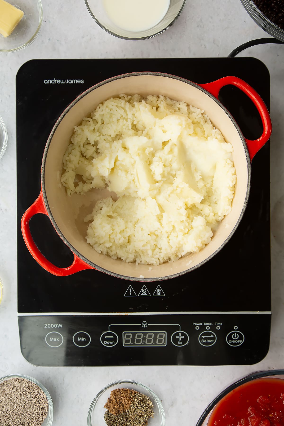 a large pan on an induction hob filled with mashed potato.