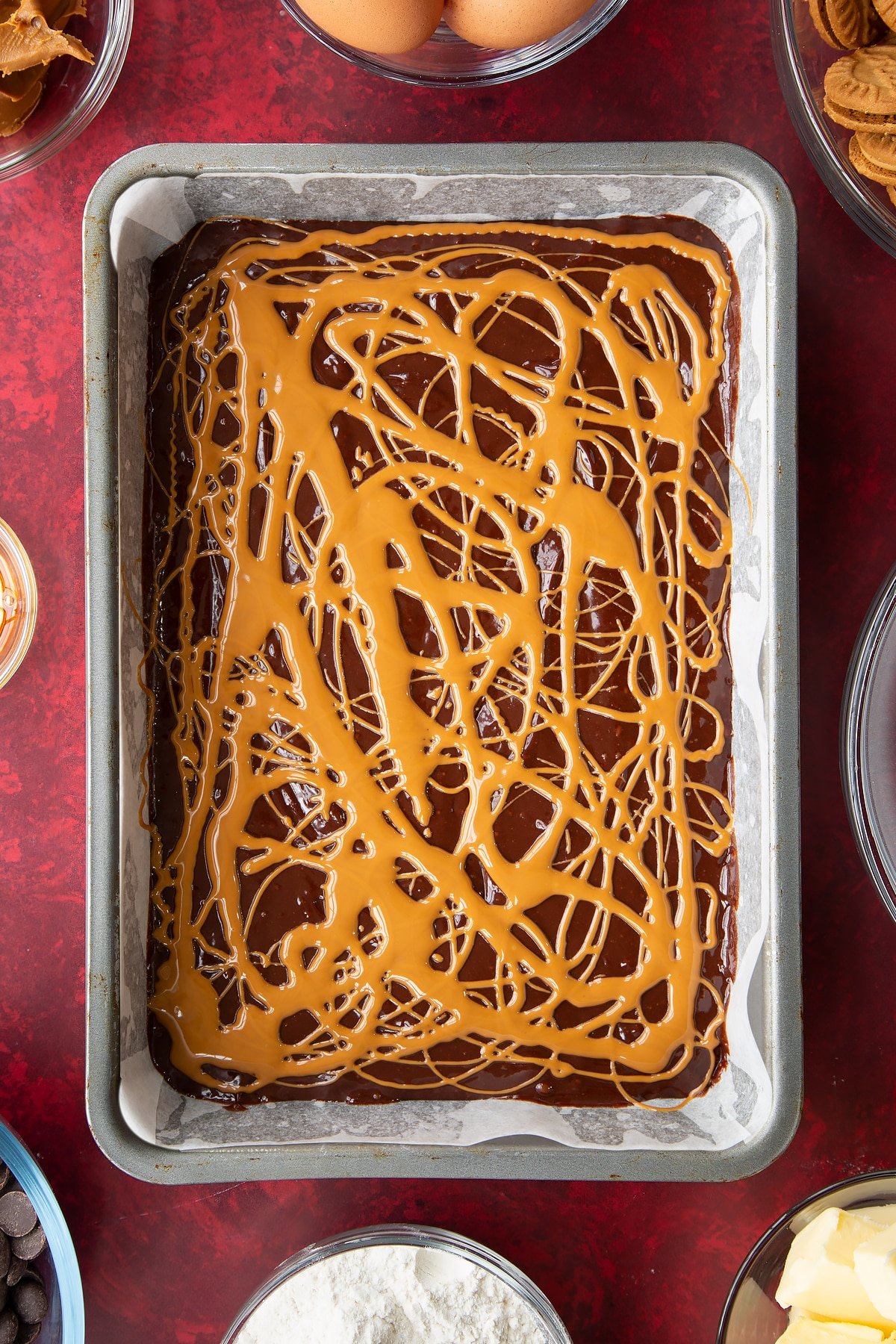 brownie batter in a lined baking tin drizzled with biscoff spread.
