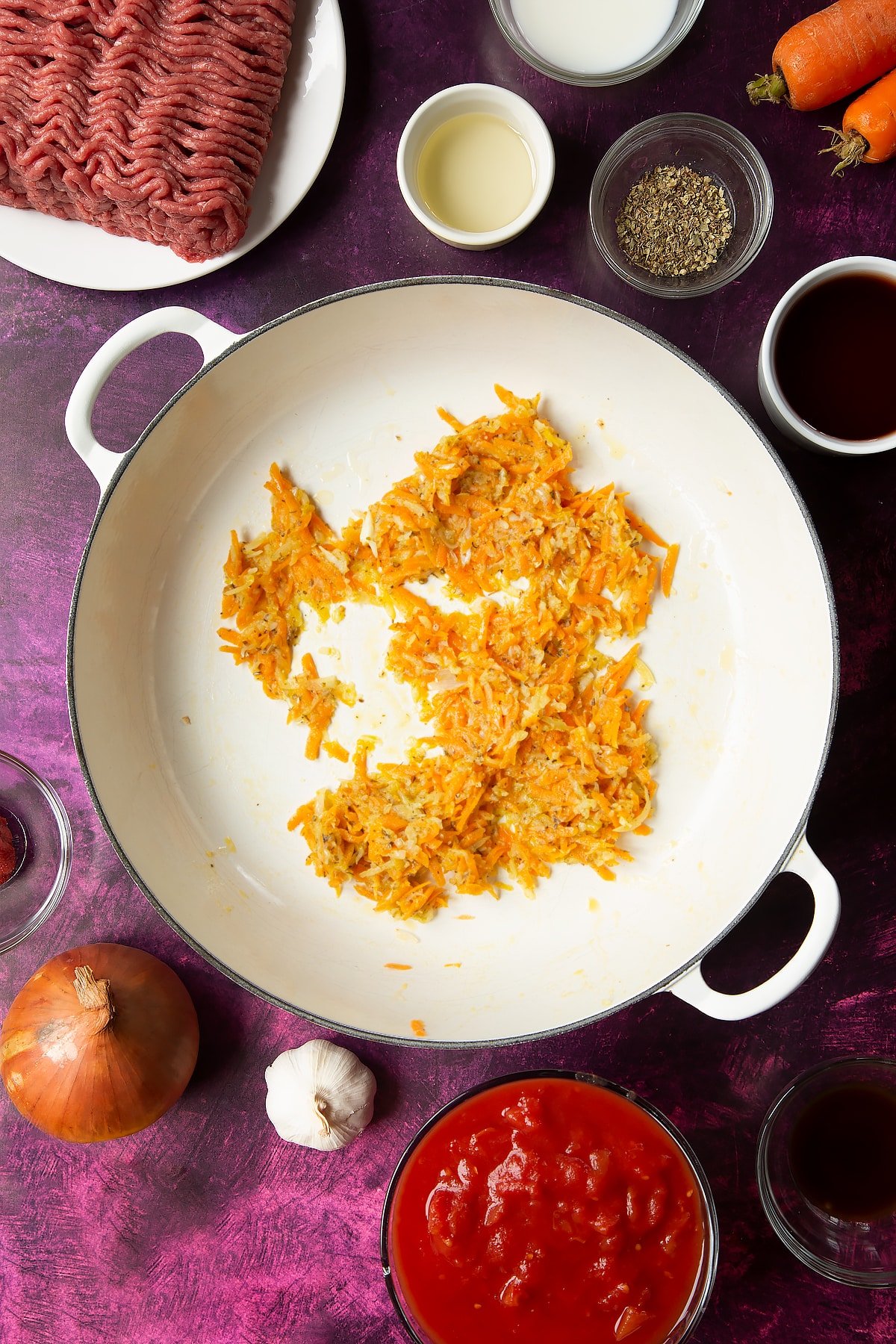 cooked oil, carrot, onion, garlic, oregano in a large white frying pan.