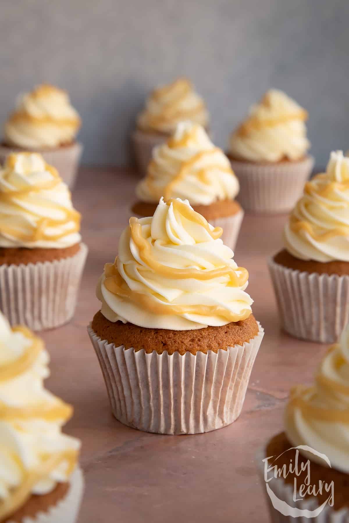 Caramel latte cupcakes lined up on a plain background.