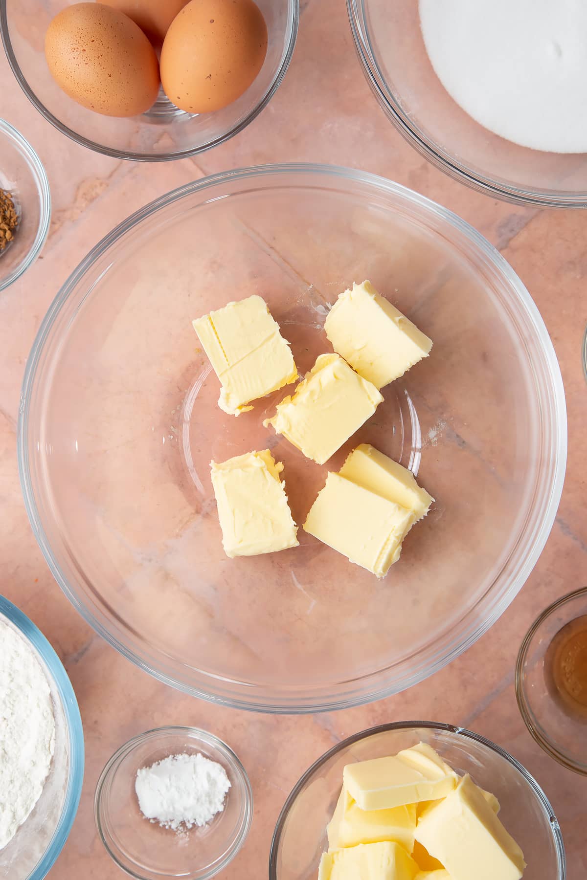 chunks of butter in a large clear bowl surrounded by ingredients.