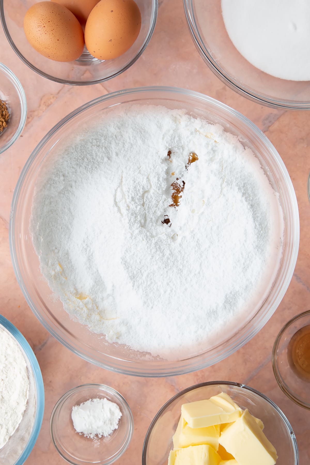 whisked butter in a large clear bowl topped with flour, milk and vanilla essence.