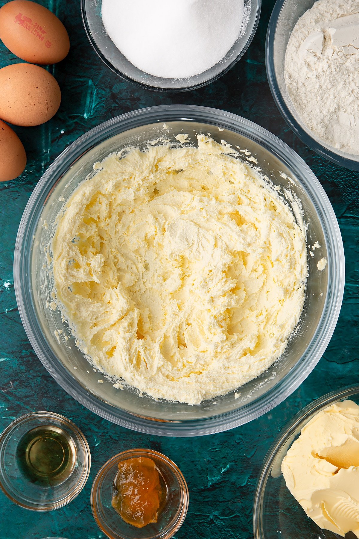 creamed sugar and margarine in a large mixing bowl with ingredients in the background.