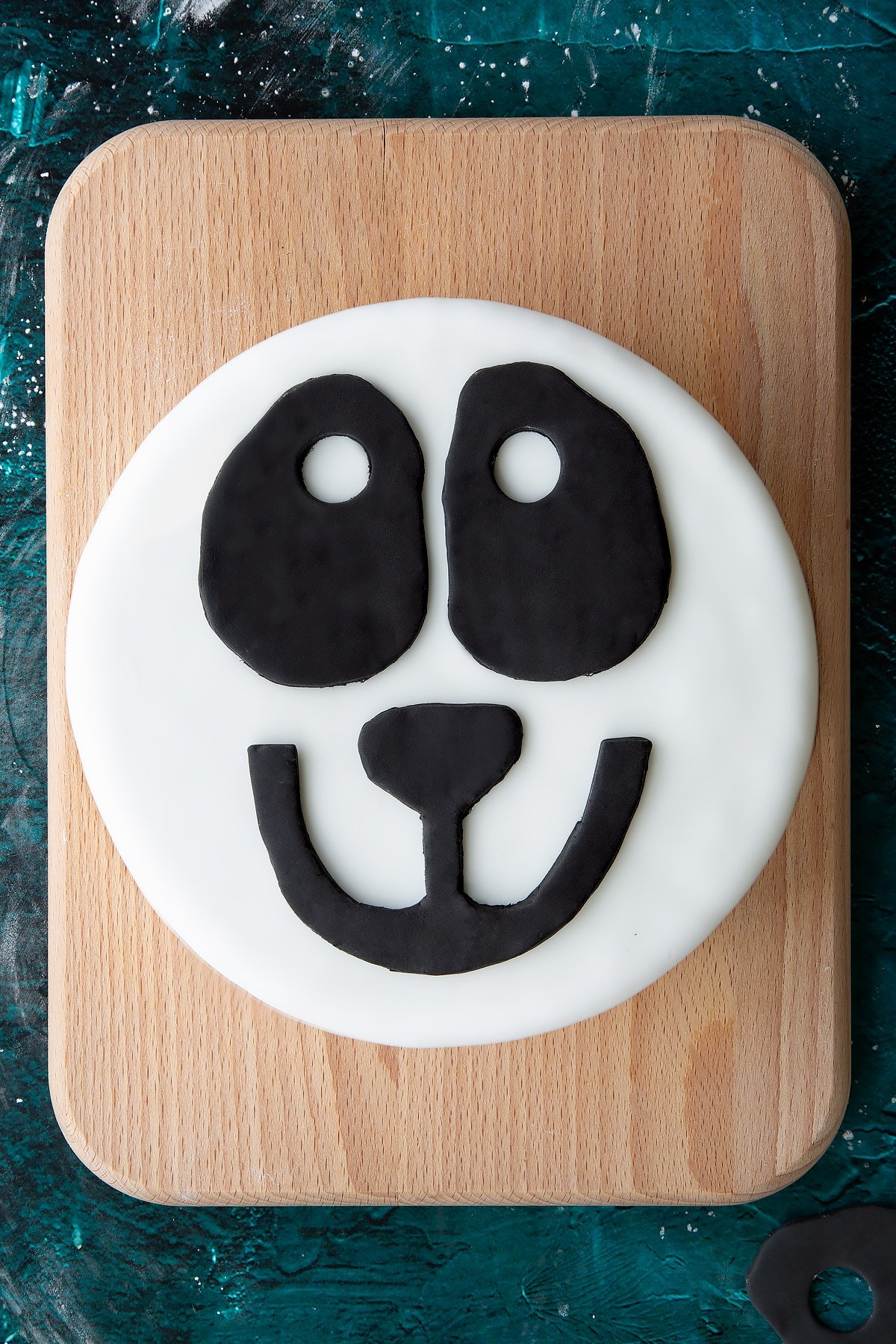 black royal icing panda features on a white royal icing covered cake on a green marble background