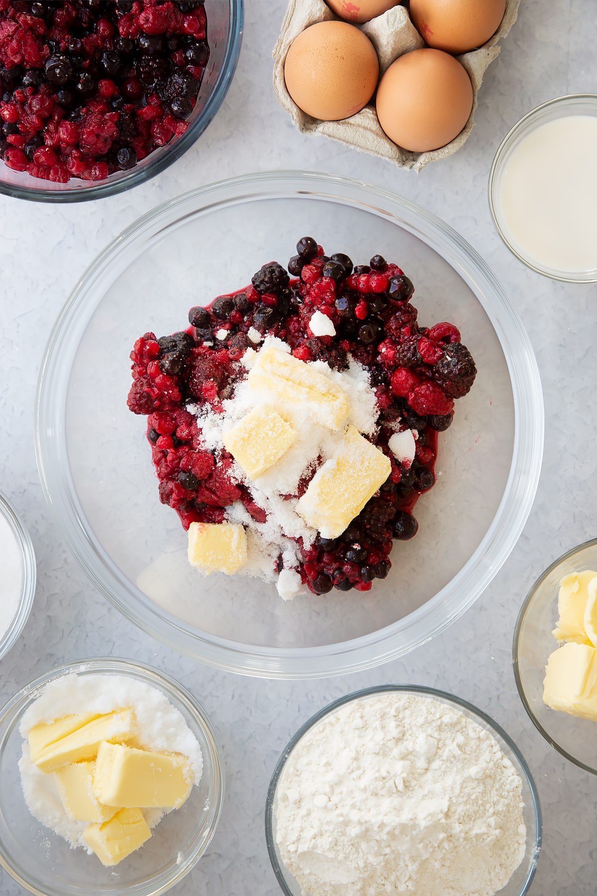 frozen fruit, butter and sugar in a large clear bowl.