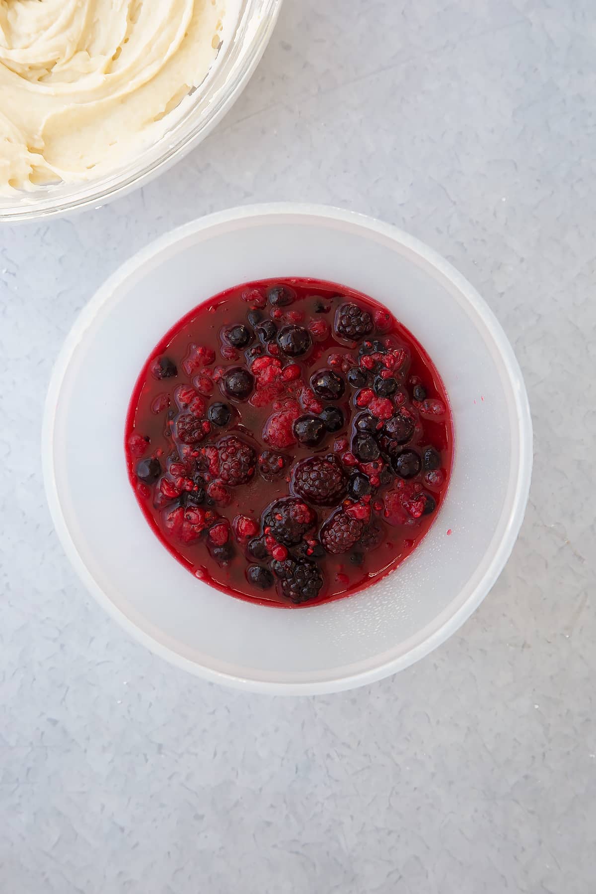 fruity mixture in the bottom of a pudding basin on a plain background.