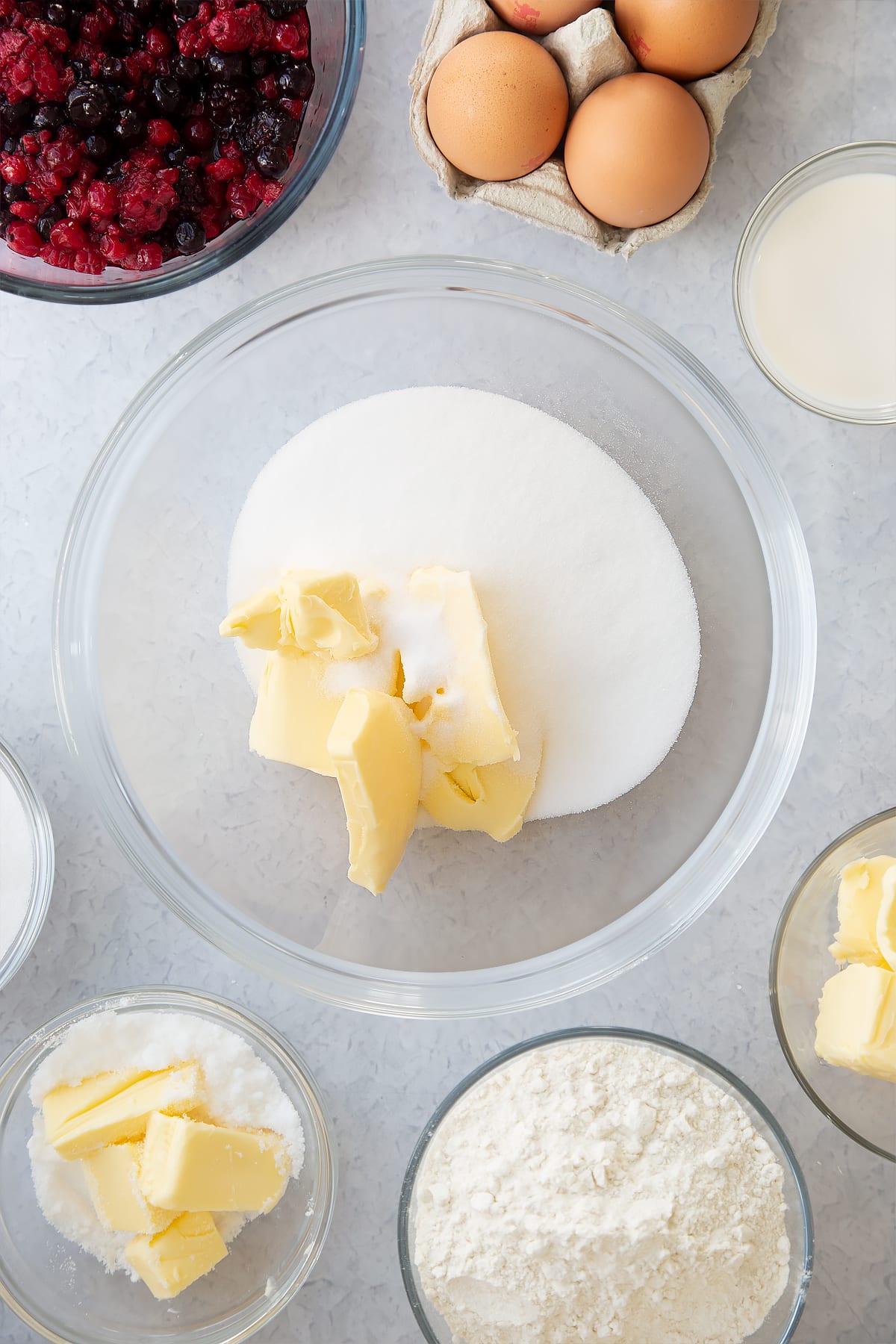 sugar and butter in a large clear bowl surrounded by ingredients.