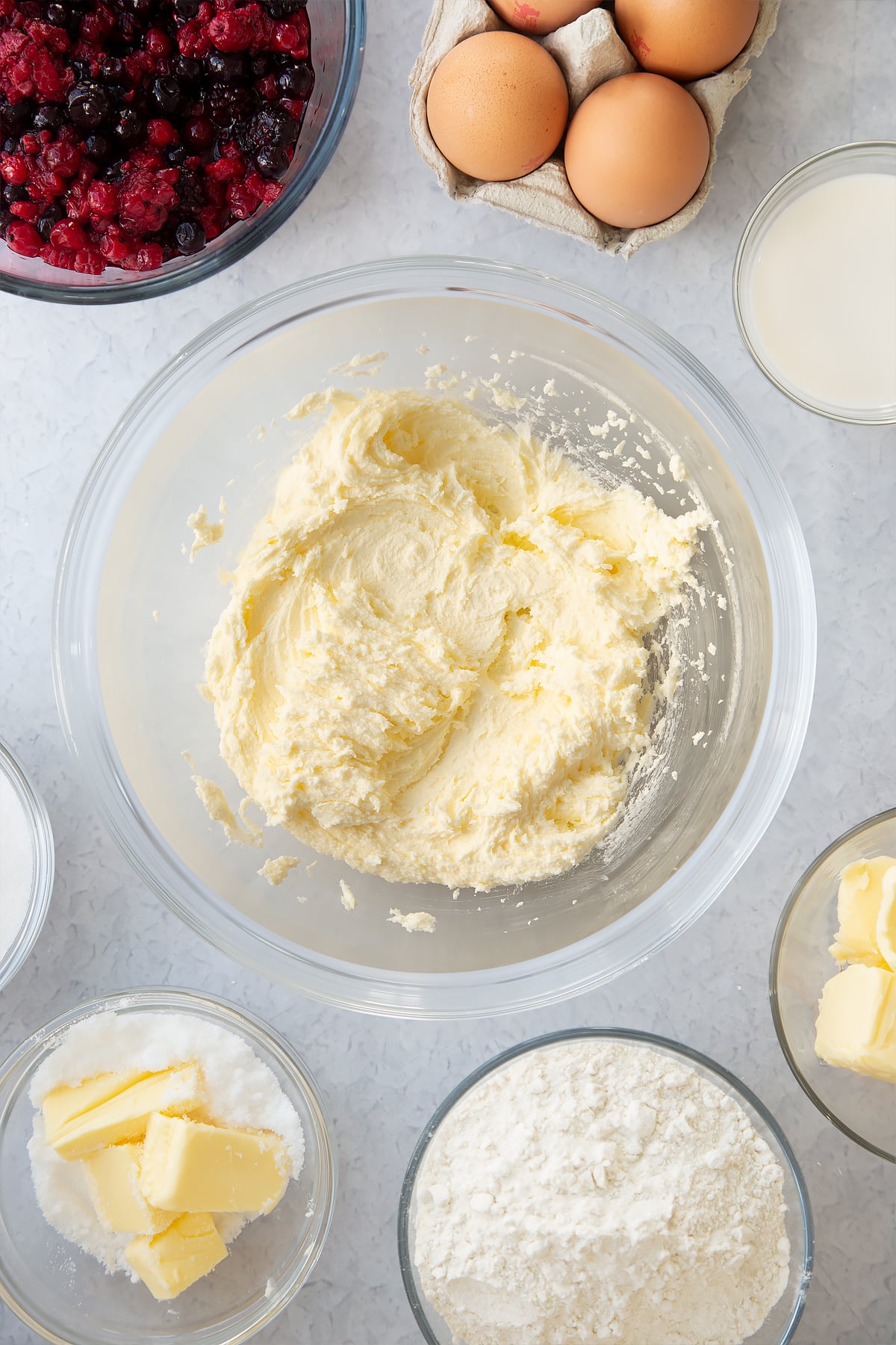 whisked sugar and butter in a large clear bowl surrounded by ingredients.