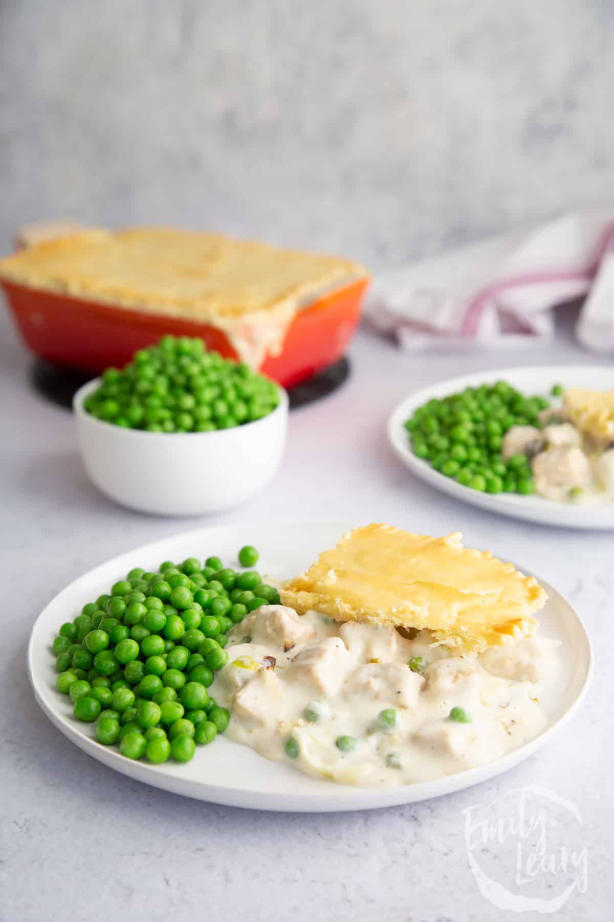 a piece of Gluten free vegetarian pie on a white plate with garden peas on the side.