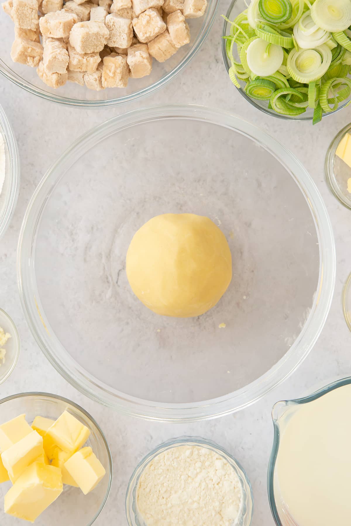 a smooth dough ball in a large clear bowl.