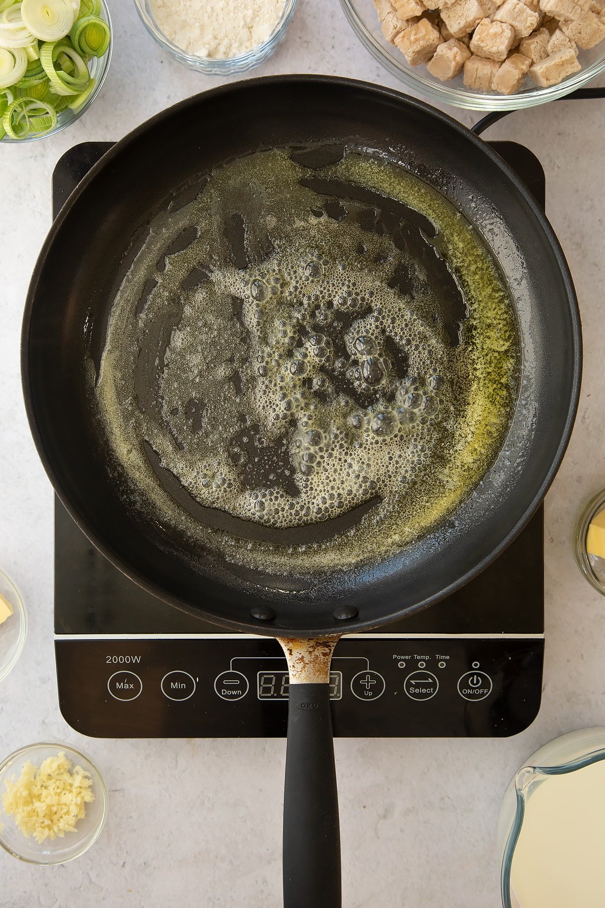 melted butter in a large frying pan on an induction hob.