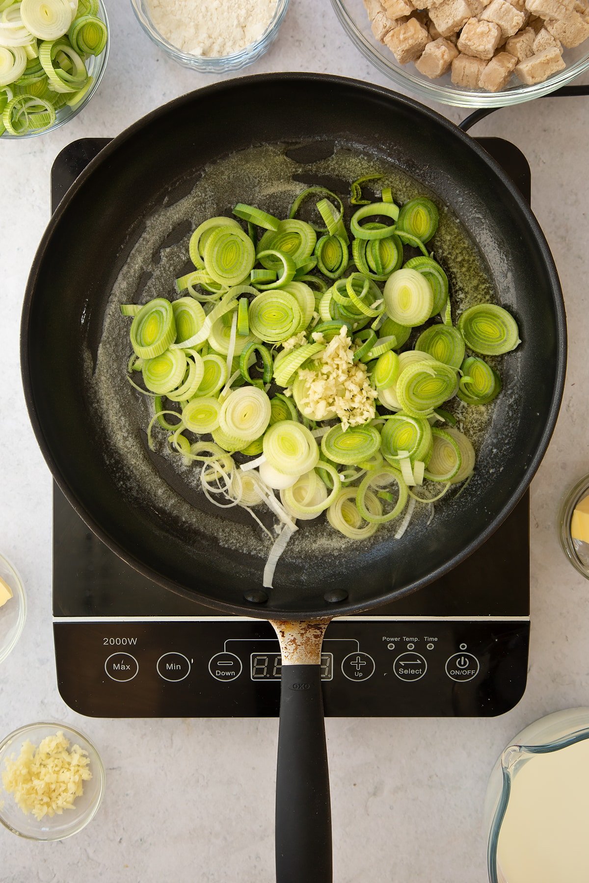 melted butter in a large frying pan topped with sliced leeks and minced garlic. 