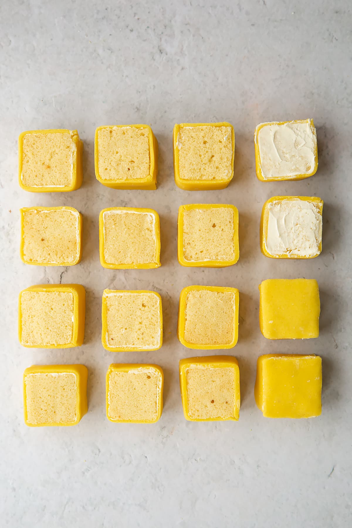 Spreading buttercream to the tops of the cake sqauares and covering in the remaining marzipan.