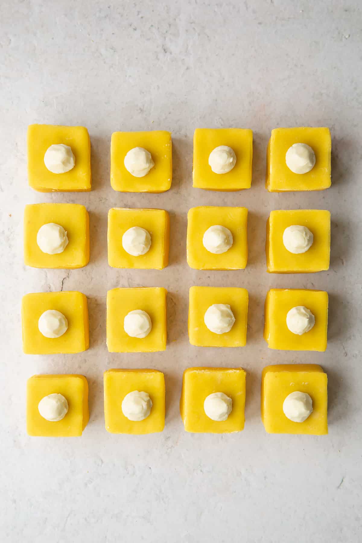 Adding the buttercream topping to each of the lemon fondant fancies. 