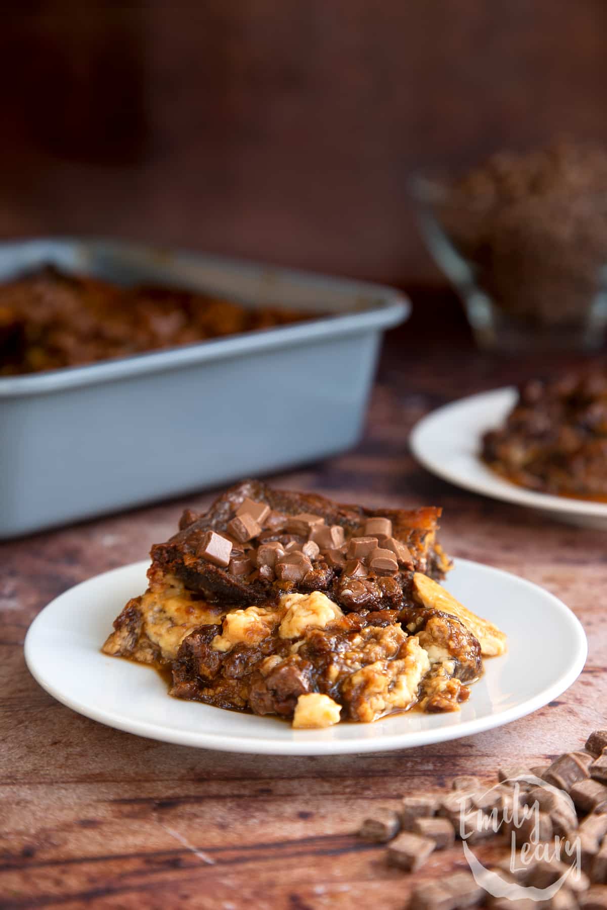 Malt loaf bread and butter pudding on a white plate with the main dish in the background.