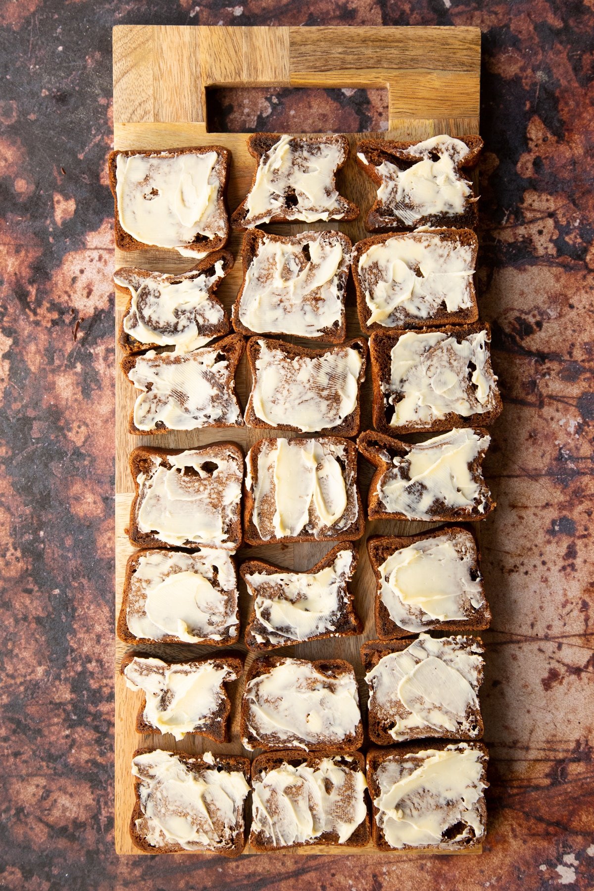 generously buttered malt loaf slices on a wooden chopping board.