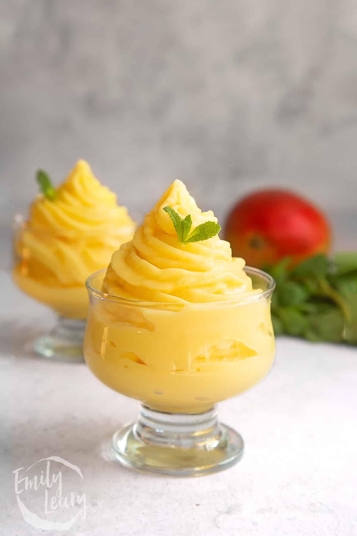 a decadent glass filled with swirled mango ice cream topped with a small mint leaf.